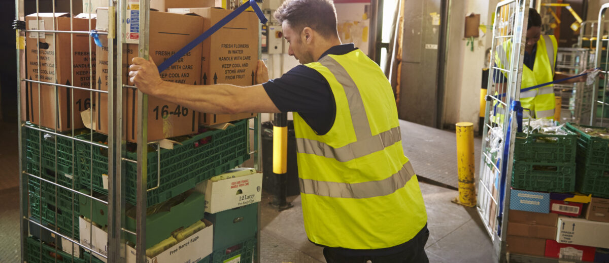 Man pushing a roll cage ready for delivery in a warehouse