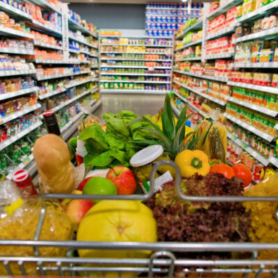 a shopping cart standing in a corridor of a supermarket in the stacks.